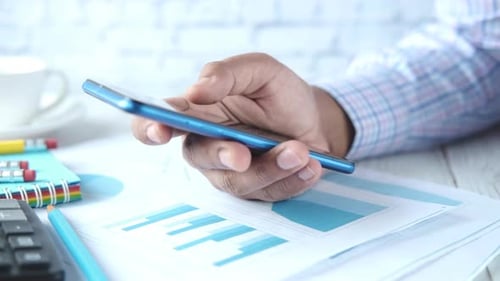 Businessman Working on Smart Phone on Office Desk