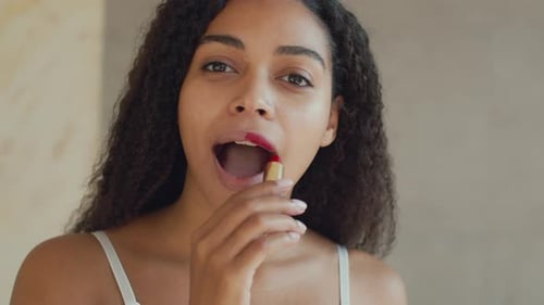 Young Beautiful African American Woman Applying Red Lipstick on Lips Preparing for Date at Home