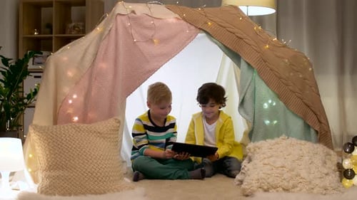 Two Children Enjoying Tablet in Blanket Fort
