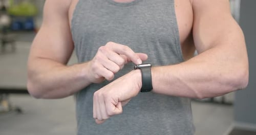 Muscular Man Using Smart Watch Device in Gym