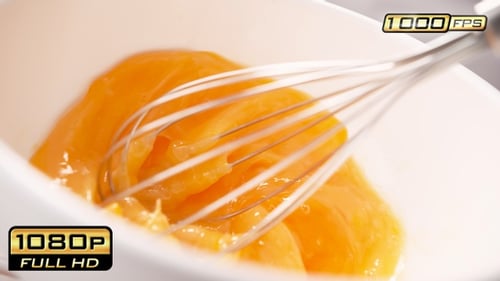 Whisk Mixing Raw Egg Yolks in White Bowl