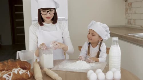 Family Spends Time Together Breaking the Eggshell and Putting Egg to the Flour While Baking Food