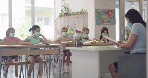Children in the Classroom at School in Masks Sit in the Classroom and Listening the Teacher