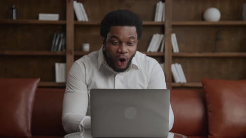 Young Adult Businessperson Recieving Good News on His Laptop in Loft Office
