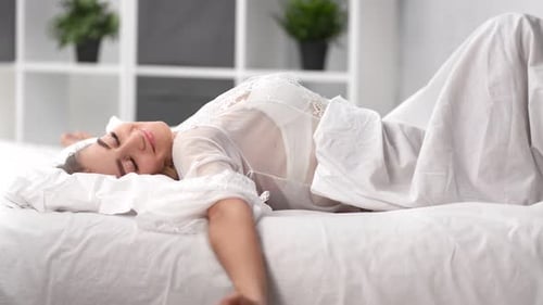 Woman Stretches Lying on Bed in Bedroom