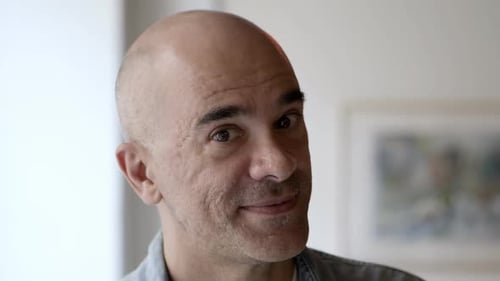 Bald Man Smiling, Wearing Earring and Denim Shirt