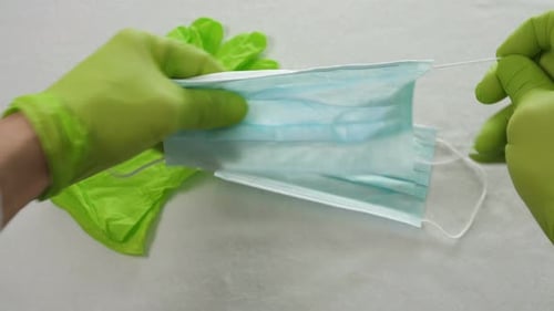 Doctor Showing Respiratory Face Mask Holding Equipment in His Hands Protected By Green Medical