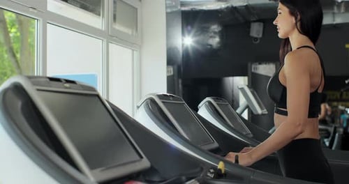 Young Athletic Man and Woman Exercising and Running on Treadmill in Sport Gym