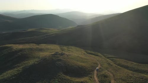 Véhicule tout-terrain conduisant sur les montagnes au coucher du soleil en vue aérienne