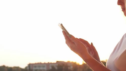 Girl Uses Smartphone By the Sea on the Sunset. Slow Motion