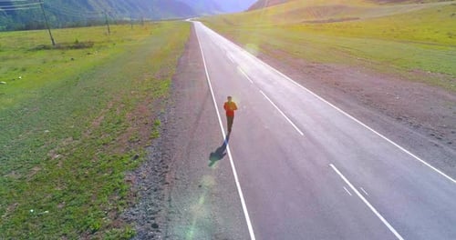Low Altitude Flight in Front of Sporty Man at Perfect Asphalt Road