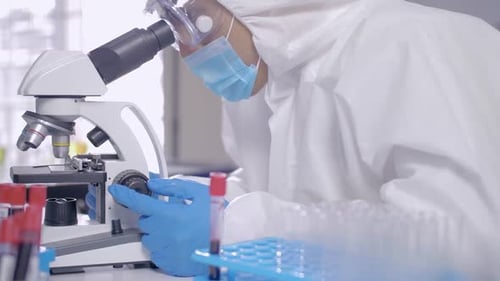 Scientist Using Microscope in a Lab with Blood Samples