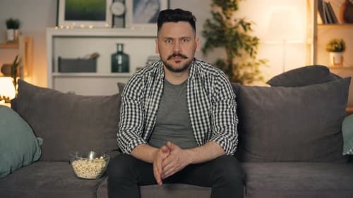 Man Reacts to Suspenseful TV Show at Night