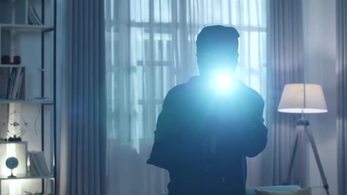 Person with Flashlight and Ski Mask Indoors at Night