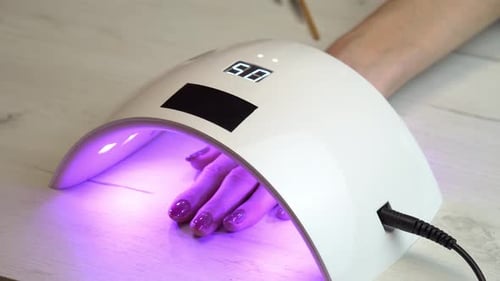 Woman Getting Manicure Under Electronic Nail Lamp