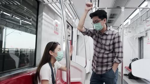 Woman and Man Talk on Train Wearing Masks