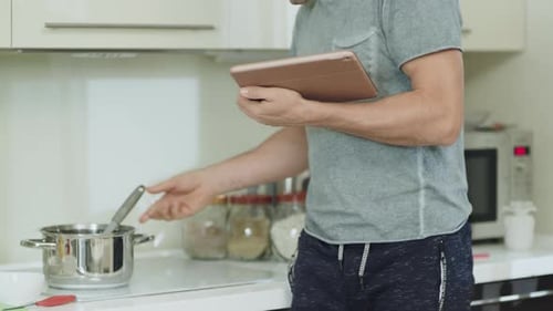 Man Follows Recipe on Tablet While Cooking in Kitchen