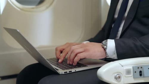 Man Typing on Laptop on an Airplane
