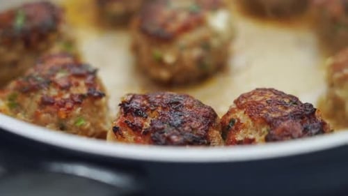 Unrecognizable person cooking meatballs on frying pan with oil