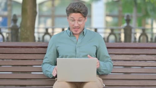 Man Using Laptop for Video Call in Park