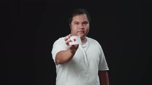 Young Adult Shows Playing Card on Black Background