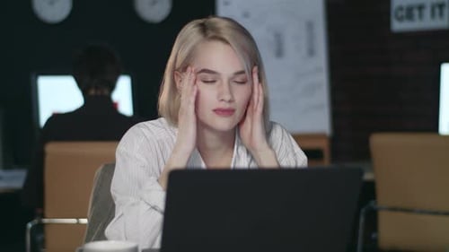 Overworked Woman Having Headache in Night Office. Stressed Woman Working Late