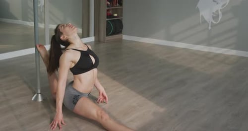 Woman Stretching Leg Holding Pole in Studio