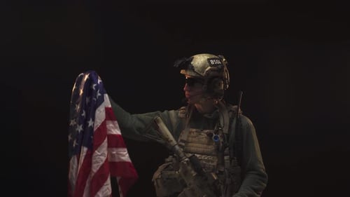 Soldier Holds American Flag in Dark Studio