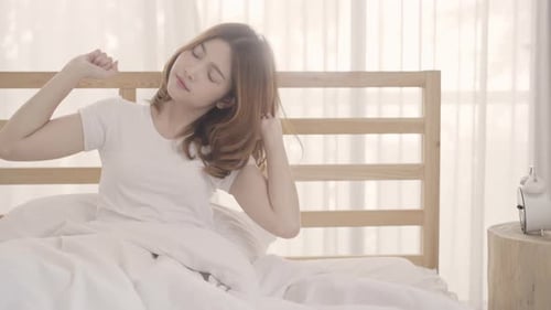 Woman Wakes Up and Stretches in Bed