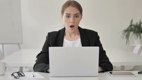 Young Woman Shocked Looking at Laptop in Office