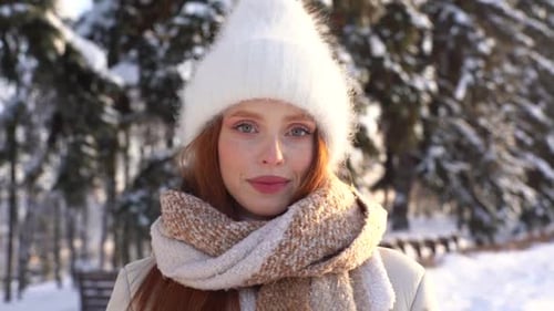 Closeup Portrait of Charming Smiling Young Woman in Warm Hat and Scarf Looking at Camera Outdoors on