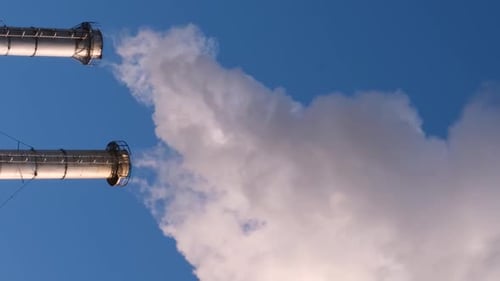 Two Smokestacks Billowing Smoke on Clear Day