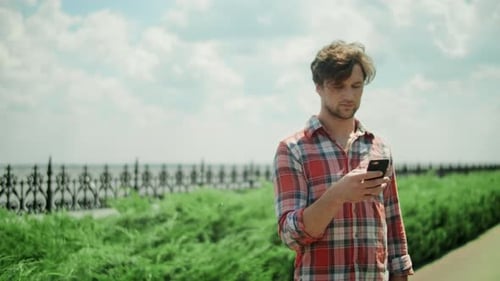 Focused Man Using Mobile Phone in Park. Serious Guy Standing on Road Outdoors