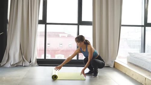 Woman Unrolls Yoga Mat for Exercise Indoors