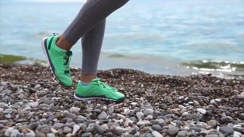 Close Up Shot of the Feet of a Young Woman, She Runs Along the Stony Bank