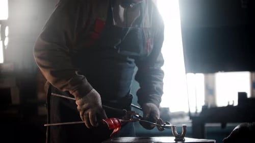 Blacksmith Workshop a Man Works with Heated Detail Using Forceps