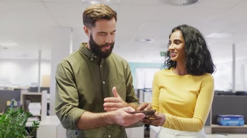 Video of happy diverse businesswoman and businessman using tablet and talking in office