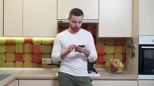 Young Adult Using Phone in Sunny Kitchen