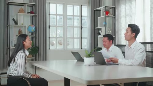 Deux hommes d'affaires asiatiques debout et serrant la main d'une femme avant de l'interviewer