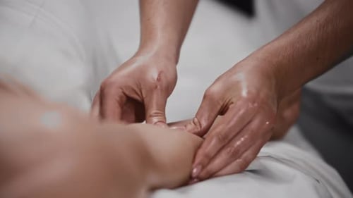 Frau erhält eine Massage und massiert ihre Hand mit einem Öl