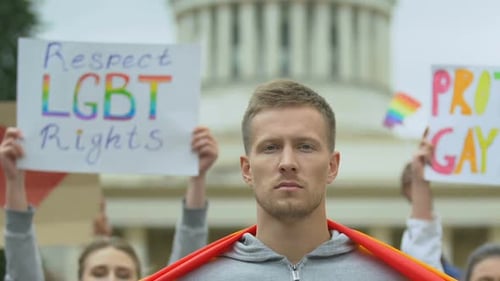 Young Man Raising Rainbow Flag, LGBT Rights Rally Participant, Pride March