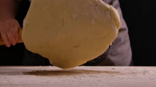 Baker Flattening Dough with Wooden Rolling Pin