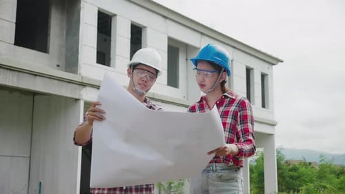Dois engenheiros de construção se reunindo em um prédio imobiliário em uniforme de segurança.