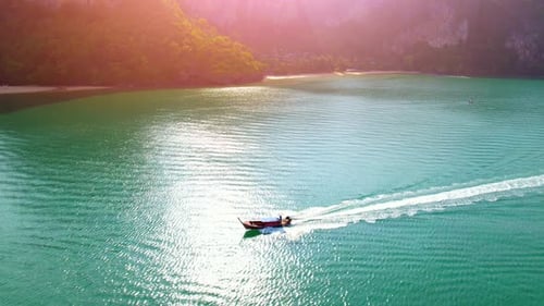 4K aerial view over a ship sailing at sea, mountains in the background.