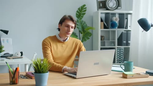 Man Typing on Laptop at Desk Indoors