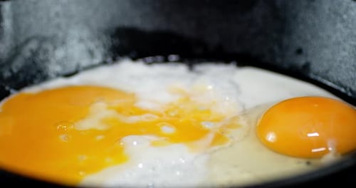 The Egg Is Fried in Oil in a Frying Pan with Air Bubbles.