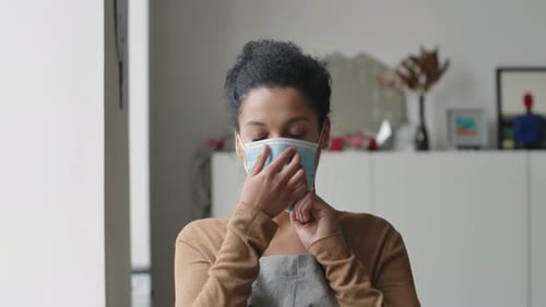 Adult Woman Putting on Surgical Face Mask Indoors