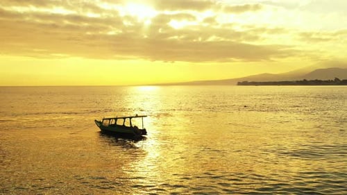Incredible Deep Gold Colored Sunset, dramatic sky , water reflection and fishing boat in the open se
