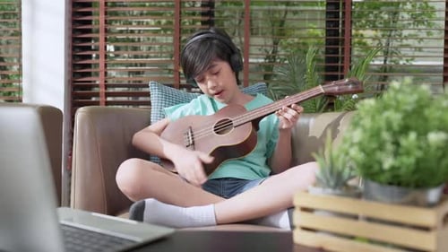 Boy Plays Ukulele and Sings at Home