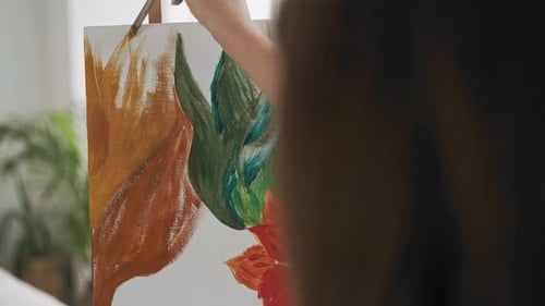 Talentierter Künstler macht orange Striche und zeichnet tropische Pflanzen